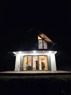 a small white house with a window at night at Okno Na Góry in Klikuszowa