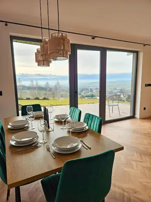 a dining room with a table with chairs and a large window at Okno Na Góry in Klikuszowa