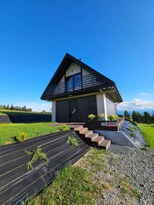 a house with a black roof and a wooden deck at Okno Na Góry in Klikuszowa