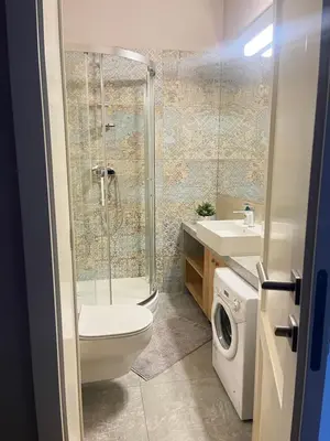a bathroom with a shower toilet and a washing machine at Studencka st Studio in Kraków