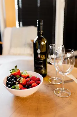 a bowl of fruit and a bottle of wine and two wine glasses at DOMKI NA LUZIE w górach PREMIUM , dla dorosłych i młodzieży in Spytkowice