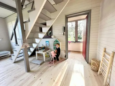 a woman sitting at a desk in a room with stairs at PrzyTuLasek - domek pod lasem w sercu natury, blisko Energylandii in Zator