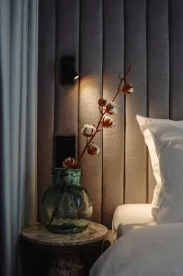 a vase with flowers on a table next to a bed at MameHome Apartments in Kraków