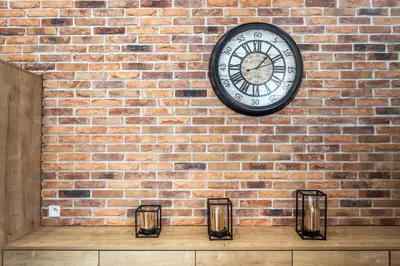 a clock hanging on a brick wall with candles at RentPlanet - Apartament Wieliczka in Wieliczka