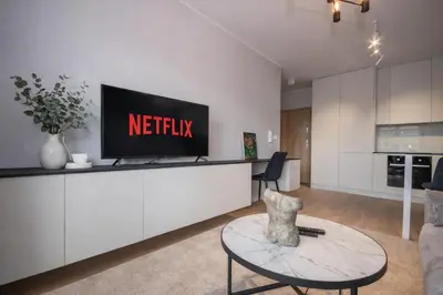 a living room with a tv on a white wall at InPoint Modern Apartment Lema 17-Tauron Arena & Free Parking Self Check-in in Kraków