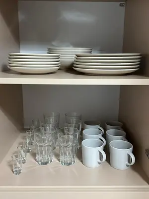 a shelf with dishes and cups and plates on it at Bartosówka Apartament in Rajbrot