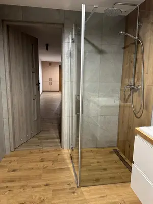 a glass shower in a bathroom with a hallway at Bartosówka Apartament in Rajbrot