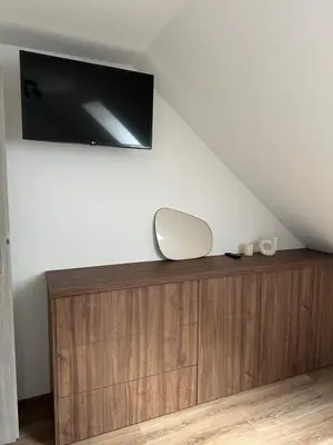 a flat screen tv on top of a wooden dresser at Bartosówka Apartament in Rajbrot