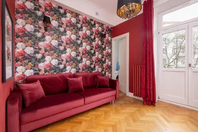a red couch in a room with a floral wall at Luxury Apartment with Two Bedrooms and Balcony by Renters Prestige in Kraków