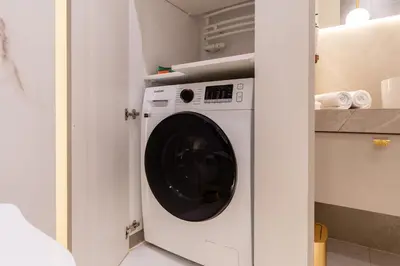 a washing machine in a white cabinet in a kitchen at Glossy Apart G29 in Kraków