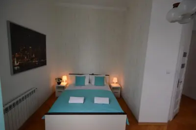 a bedroom with a bed with blue sheets and two lights at Royal Castle Apartments in Kraków