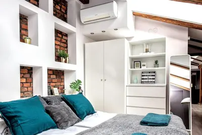 a bedroom with white walls and a bed with blue pillows at Exclusive loft with Sauna, AC and 3 bathrooms in Kraków