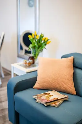 a blue couch with a pillow and a magazine on it at Florencja Moxy TE&AM Stare Miasto Dworzec 3 min Parking GRATIS in Kraków
