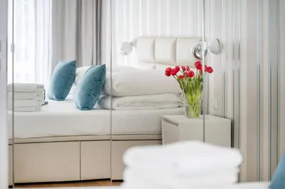 a white couch with blue pillows and a vase of flowers at Rimini Moxy TE&AM Old Town Free Parking Dworzec 5 min in Kraków