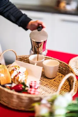 a person is pouring coffee into a cup next to a basket of food at Perugia Moxy TE&AM Old Town Parking gratis in Kraków