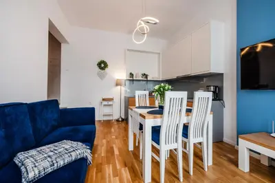a living room with a blue couch and a table and chairs at Wenecja Moxy TE&AM Stare Miasto Dworzec 3 min Parking GRATIS in Kraków