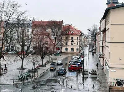 a city street with cars parked in the rain at Once Upon a Time in Cracow - Old Town Apartment in Kraków