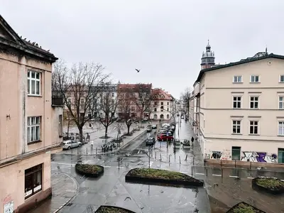 a city street in the rain with cars and buildings at Once Upon a Time in Cracow - Old Town Apartment in Kraków