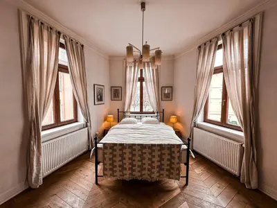 a bedroom with a bed in a room with windows at Once Upon a Time in Cracow - Old Town Apartment in Kraków