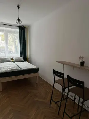 a room with a bed and two chairs and a window at Rooms in City Center Kraków in Kraków