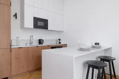 a kitchen with a white counter and two stools at Słowackiego Elegant Apartment Kraków by Noclegi Renters in Kraków