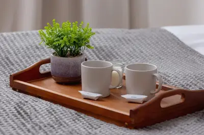 a tray with two cups and a potted plant on a bed at Słowackiego Elegant Apartment Kraków by Noclegi Renters in Kraków