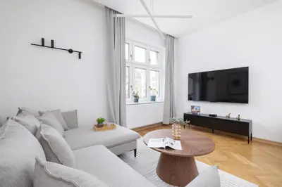 a white living room with a couch and a tv at Słowackiego Elegant Apartment Kraków by Noclegi Renters in Kraków