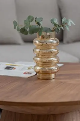 a gold vase with a plant in it on a table at Słowackiego Elegant Apartment Kraków by Noclegi Renters in Kraków