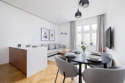 a kitchen and living room with a table and chairs at Słowackiego Elegant Apartment Kraków by Noclegi Renters in Kraków