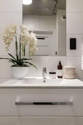 a white bathroom with a sink with a vase of flowers at NEW place next to Vistula & Wawel Castle in Kraków