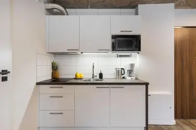 a white kitchen with a sink and a microwave at NEW place next to Vistula & Wawel Castle in Kraków