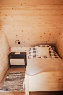 a bed in a wooden room with a lamp on a table at Domek przy szlaku in Rabka-Zdroj