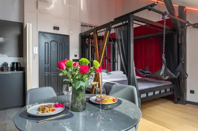 a dining room with a table with flowers and a bed at Exclusive BDSM Apartment Kraków - ADULTS ONLY in Kraków