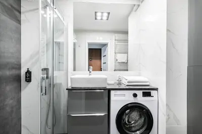 a bathroom with a washing machine and a sink at Apartamenty Platinex 1 in Kraków
