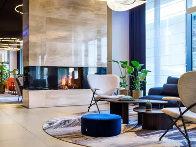 a living room with a fireplace and chairs at Hilton Garden Inn Krakow Airport in Kraków