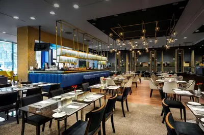 a restaurant with tables and chairs and a bar at Hilton Garden Inn Krakow Airport in Kraków