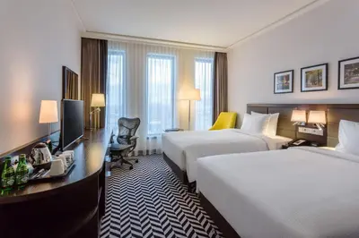 a hotel room with two beds and a television at Hilton Garden Inn Krakow Airport in Kraków