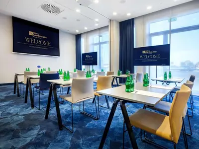 a conference room with tables and chairs with bottles on the wall at Hilton Garden Inn Krakow Airport in Kraków