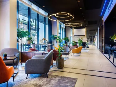 a lobby of a restaurant with chairs and tables at Hilton Garden Inn Krakow Airport in Kraków