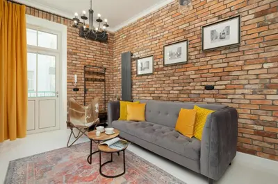 a living room with a couch and a brick wall at Dietla One Bedroom Apartments with Air Conditioning & Balcony by Noclegi Renters in Kraków