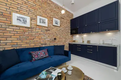 a living room with a blue couch and a brick wall at Dietla One Bedroom Apartments with Air Conditioning & Balcony by Noclegi Renters in Kraków