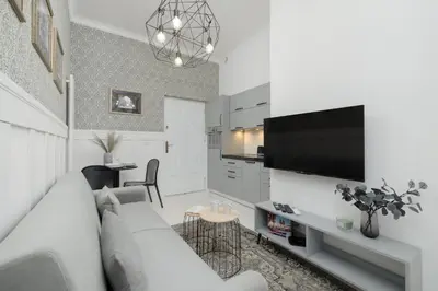 a white living room with a couch and a tv at Dietla One Bedroom Apartments with Air Conditioning & Balcony by Noclegi Renters in Kraków