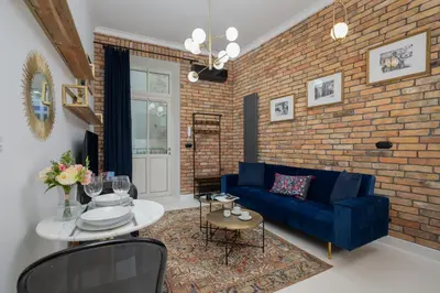 a living room with a blue couch and a brick wall at Dietla One Bedroom Apartments with Air Conditioning & Balcony by Noclegi Renters in Kraków