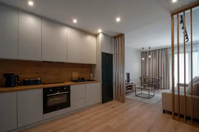 a kitchen with white cabinets and a living room at Apartament Kościuszki 47m44 in Kraków