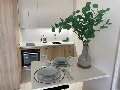 a kitchen with a table with plates and a vase with flowers at Imperial Citi Apartament in Kraków