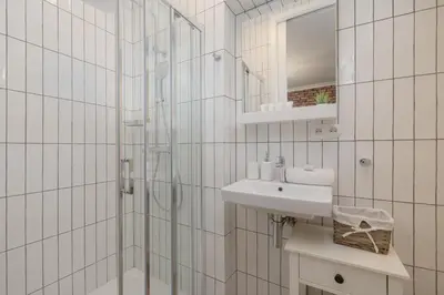 a white tiled bathroom with a shower and a sink at Beautiful & Stylish Apartaments Dietla with Air Conditioning by Noclegi Renters in Kraków