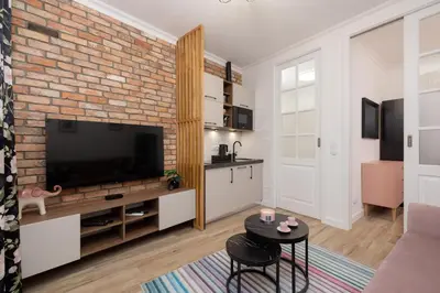 a living room with a tv and a brick wall at Beautiful & Stylish Apartaments Dietla with Air Conditioning by Noclegi Renters in Kraków