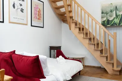 a living room with a red couch and stairs at Park Strzelecki Two-Level Apartment by BookingHost in Kraków