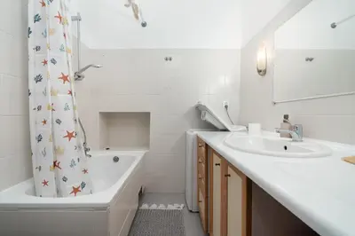 a bathroom with a sink and a tub and a shower curtain at Park Strzelecki Two-Level Apartment by BookingHost in Kraków