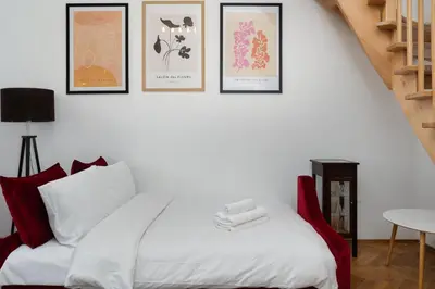 a bedroom with a white bed with four pictures on the wall at Park Strzelecki Two-Level Apartment by BookingHost in Kraków